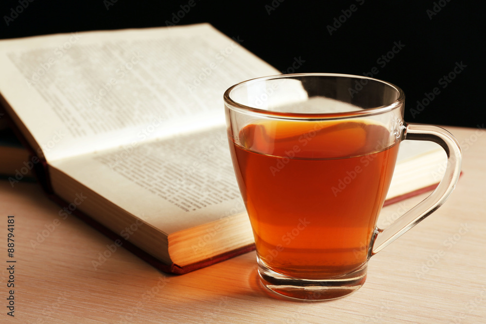 Glass cup of tea with book on wooden table, closeup Glass cup of tea with book on wooden table, closeup