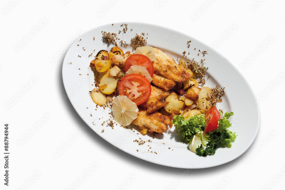 Paniertes Seelachsfilet mit Bratkartoffeln in Platte auf weißem Paniertes Seelachsfilet mit Bratkartoffeln in Platte auf weißem