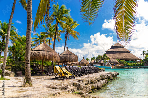 Relax in Mexico. Tropical paradise beach with sun beds under the palm trees in Xcaret park
