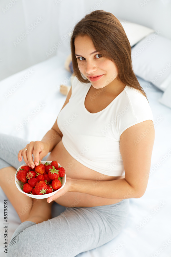 Pregnant Woman Eating Strawberry at home. Healthy Food Concept. Pregnant Woman Eating Strawberry at home. Healthy Food Concept.