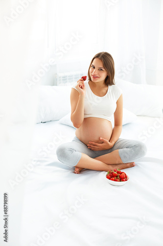 Pregnant Woman Eating Strawberry at home. Healthy Food Concept.