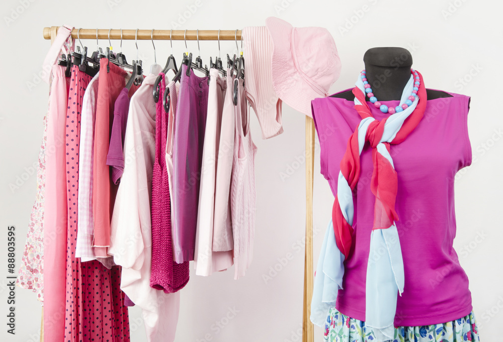 Dressing closet with pink clothes arranged on hangers and an outfit on a mannequin. Wardrobe full of all shades of pink clothes and accessories. Dressing closet with pink clothes arranged on hangers and an outfit on a mannequin. Wardrobe full of all shades of pink clothes and accessories.