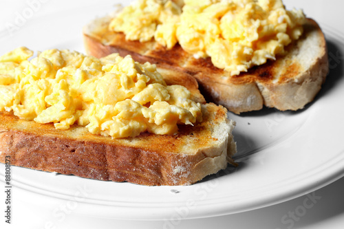 Scrambled egg on toast.
Scrambled egg on toast on a plate.
