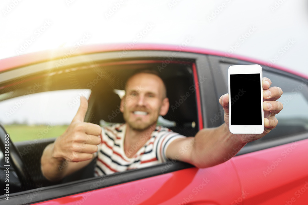 Man in car showing smart phone.