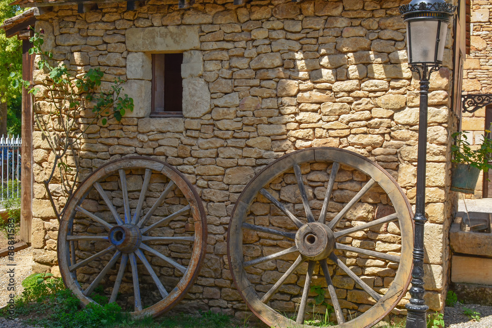 2 roues en bois contre mur en pierres