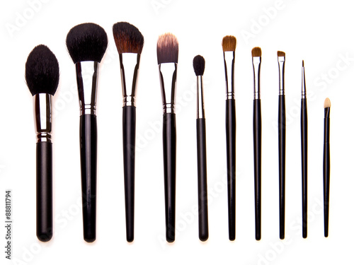 Set of essential professional make-up brushes, isolated with shadows on white background. Overhead view. Front part. Place for your text.