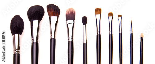 Set of essential professional make-up brushes, isolated with shadows on white background. Overhead view. Front part. Place for your text.