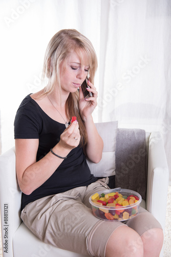 young woman on the phone eating sweets