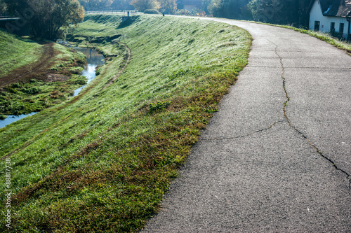 Way of gray stone with cracks on a high area of green grass with a small creek in a margin, in Szentendre's city, Budapest