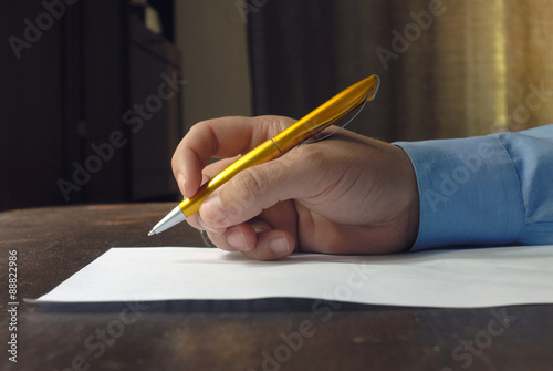 Human males hand holding pen near sheet of paper