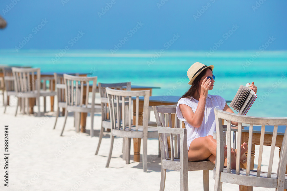 Happy girl reading on tropical white beach