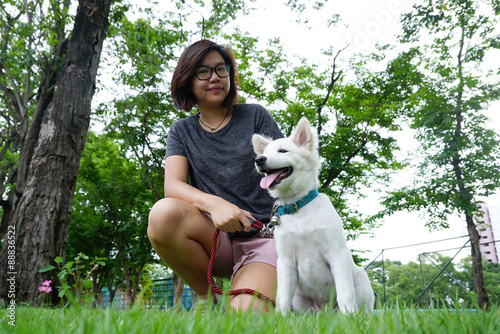 Asian woman wearing glass sitting with her white puppy
