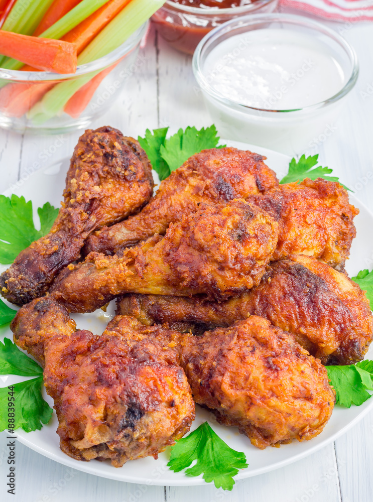 Roasted chicken served with celery and carrot sticks, blue cheese dressing and hot sauce