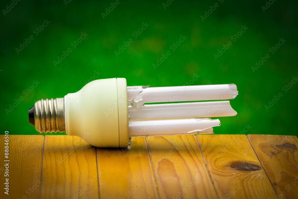 Defective bulb placed on a brown chair. Green background And pose a danger to global warming. Defective bulb placed on a brown chair. Green background And pose a danger to global warming.