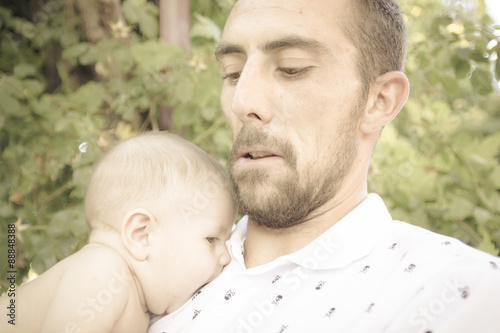Bebe en brazos de su padre jugando en el parque. Primer plano de un padre jugando con su bebe desnudo en pañal. Bebe feliz.