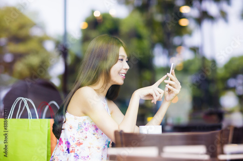 smiling young woman looking at smart phone in cafe shop