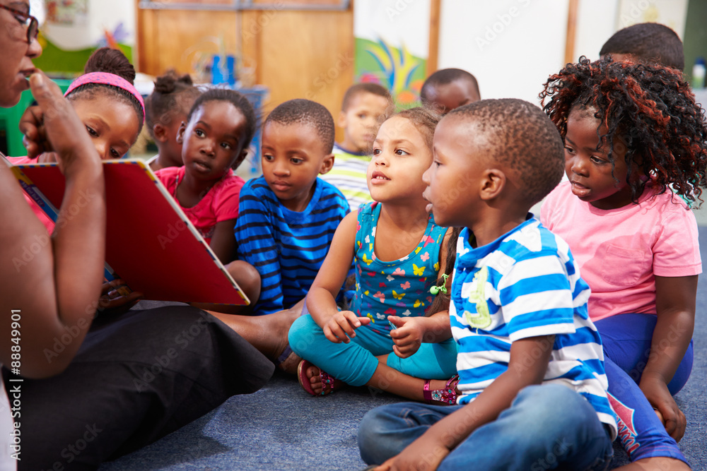 Fototapeta premium Teacher reading a book with a class of preschool children