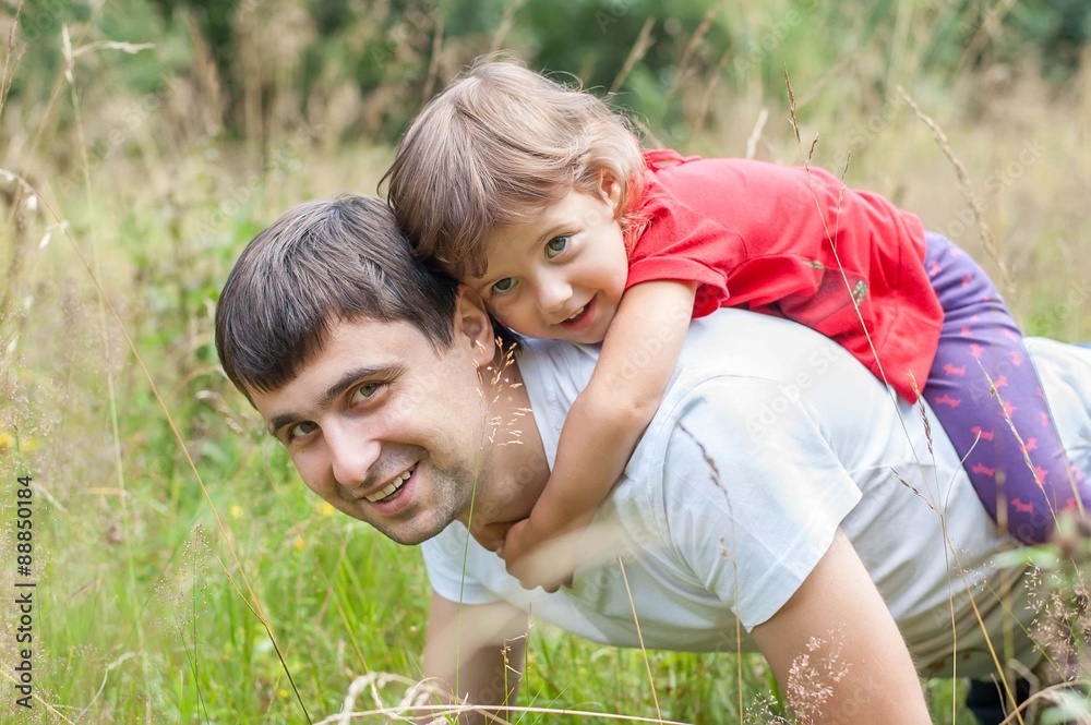 Fototapeta premium Daddy carrying little girl on his back