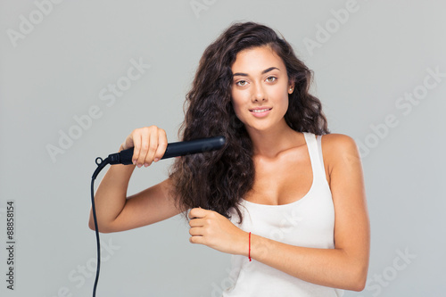 Woman doing hairstyle with hair straightener