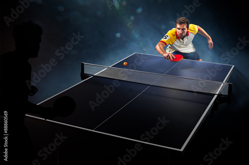 фотографія young sports man tennis player playing on black background with