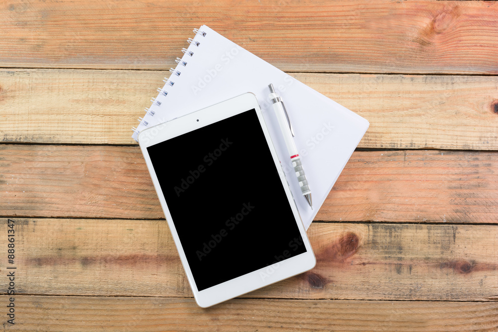Tablet device on wooden workspace table Tablet device on wooden workspace table