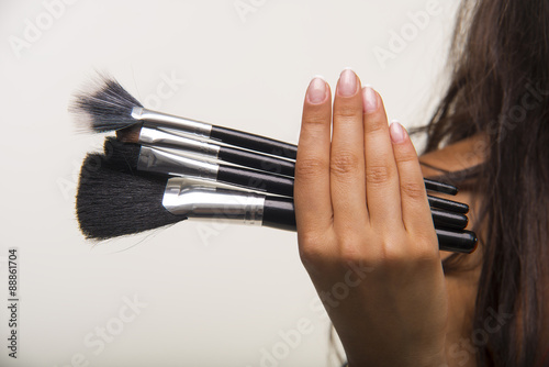 Nice lady in orange shirt is showing cosmetic brush set closeup.