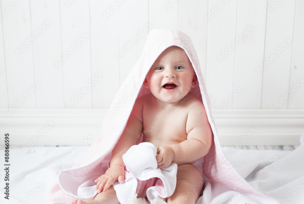 happy baby with a towel after the shower in bed at home