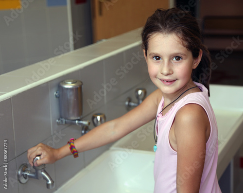 little girl is washing her hands in the sink in the bathroom of