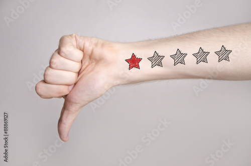 Man hand showing thumbs down and one star rating on the arm skin photo