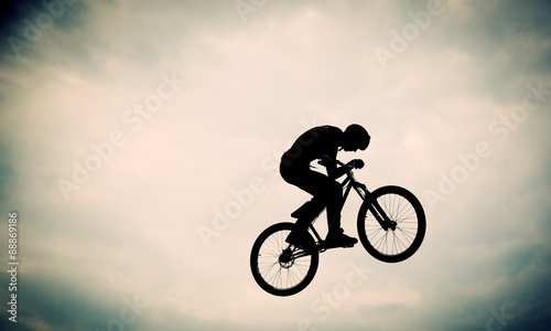 Silhouette of a man doing a jump with a bmx bike against sunset