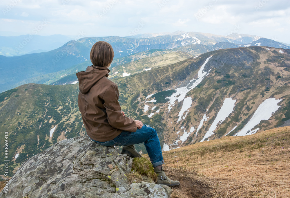 Girl is sitting on a mountain top