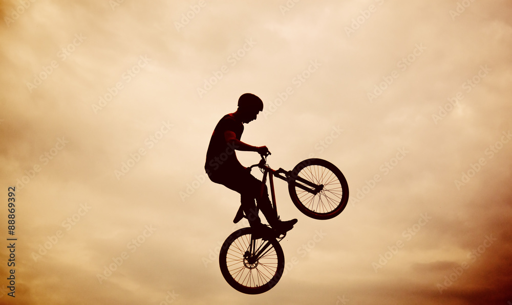 Silhouette of a man doing a jump with a bmx bike against sunset Silhouette of a man doing a jump with a bmx bike against sunset
