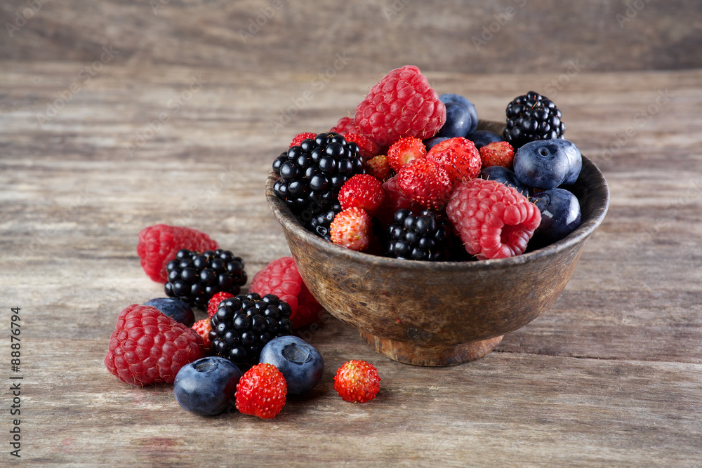 Assorted berries in bowl on wood Assorted berries in bowl on wood