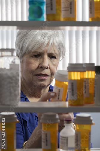 A mature woman grabbing one of her many medications