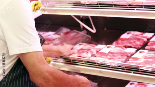 Senior worker stocking fridge in the supermarket