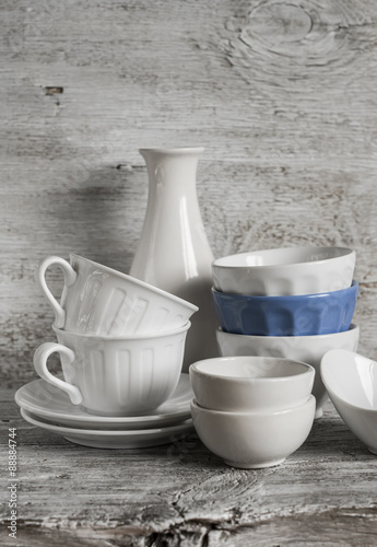 white vintage crockery - ceramic bowl, vase, porcelain tea cups on white wooden background