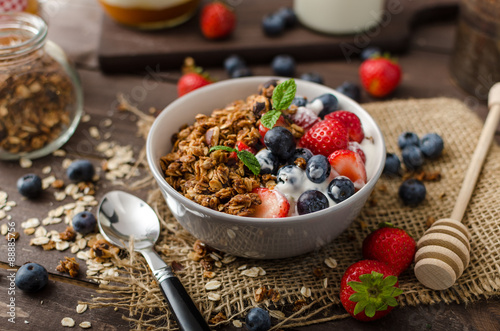 Yogurt with baked granola and berries in small bowl photo