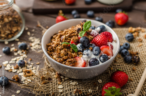 Yogurt with baked granola and berries in small bowl