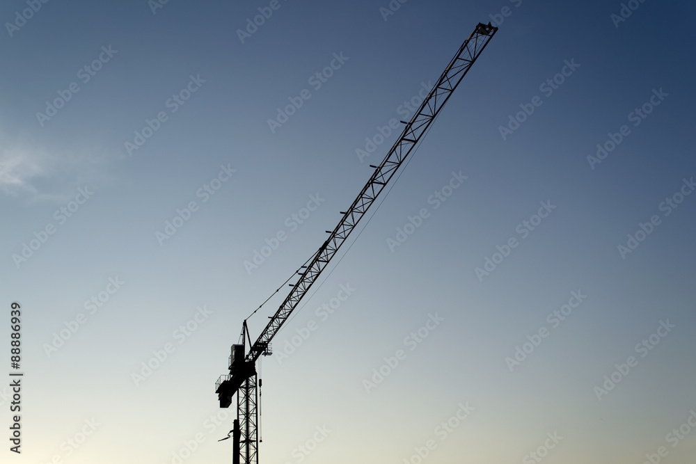 Single building crane silhouette against blue sky in evening