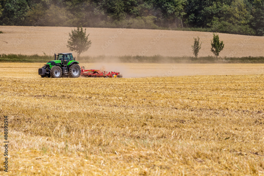 Obraz premium Tractor harvester working in rapeseed field in summer time 