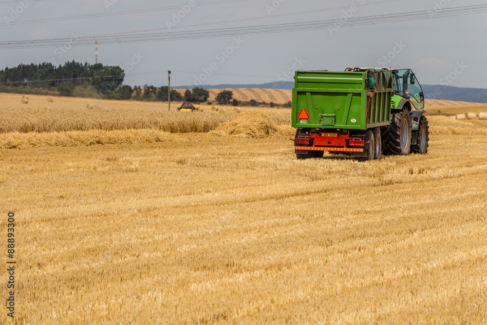Fototapeta premium Truck preparing to load hay bales on a field during harvest time