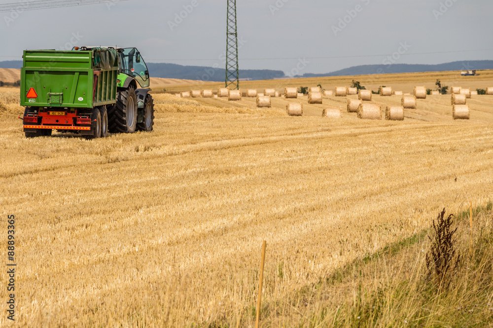 Naklejka premium Truck preparing to load hay bales on a field during harvest time