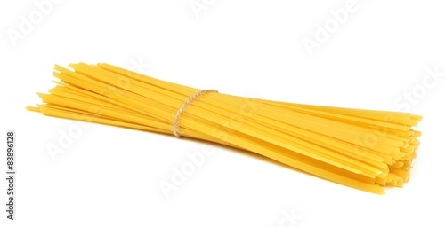 Uncooked dry fettuccine pasta tied in a bundle isolated on a white background