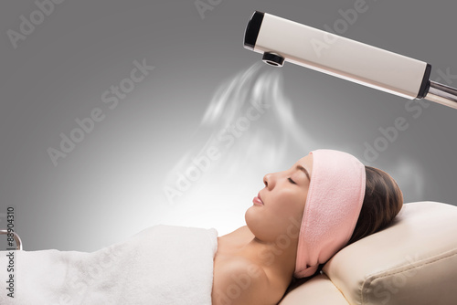 Beauty treatment of face skin with ozone facial steamer in spa center , asian women facing the steam. Steam for smooth skin