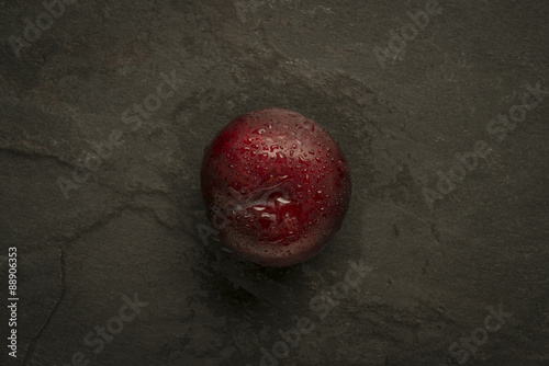 Plum with water droplets on slate
