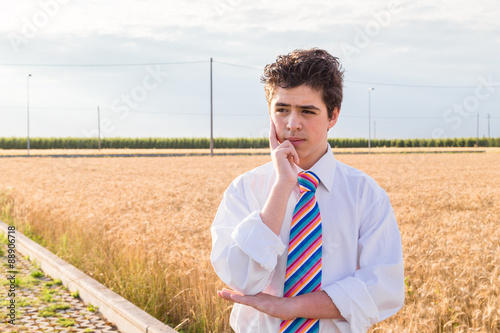 Handsome boy brooding in a golden wheat field