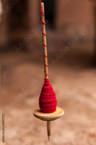fuso per filare la lana in rotazione, avvolto con lana rossa photo
