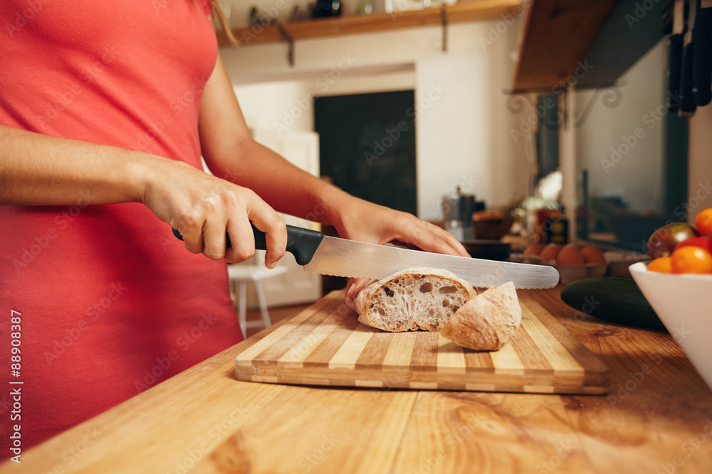 Woman slicing loaf of bread in kitchen