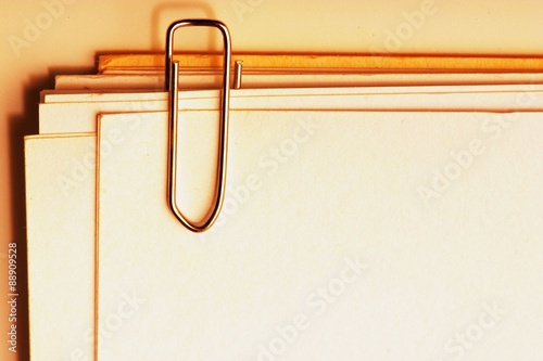view of a paper clip with stack of blank paper photo