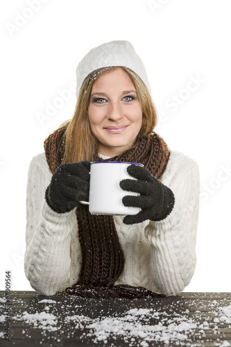 Junge Frau mit Mütze und Tasse in der Hand auf weissem Hintergrund